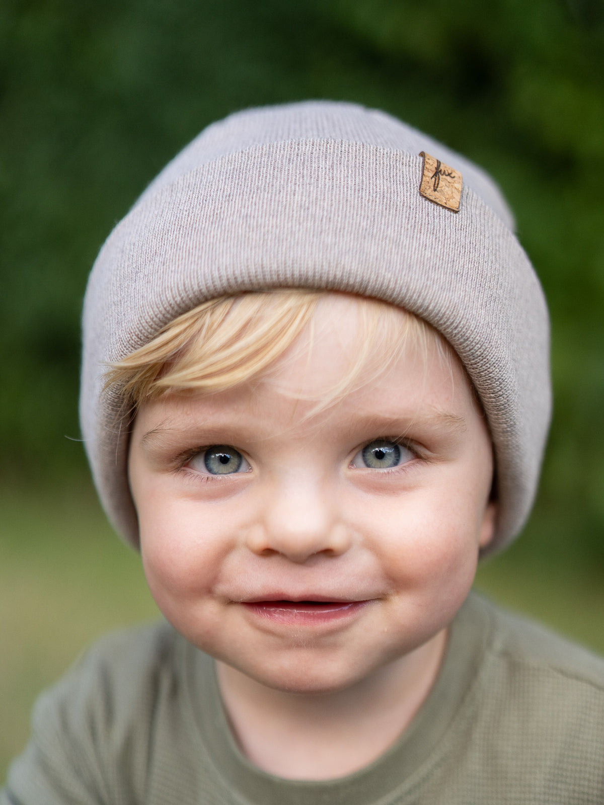 Frontalaufnahme eines Kindes mit sandfarbener FUXBAU Kinder Merino Kork Beanie aus 100% Merinowolle, fair produziert in Deutschland.