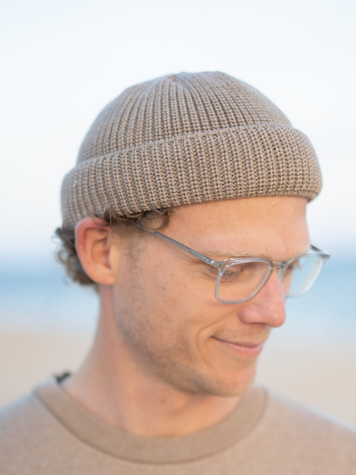 Kurze Merino Fischermütze in der Farbe sand beige aus 100% GOTS zertifizierter Merinowolle. Getragen am Strand in Portugal und fair in Deutschland gefertigt.