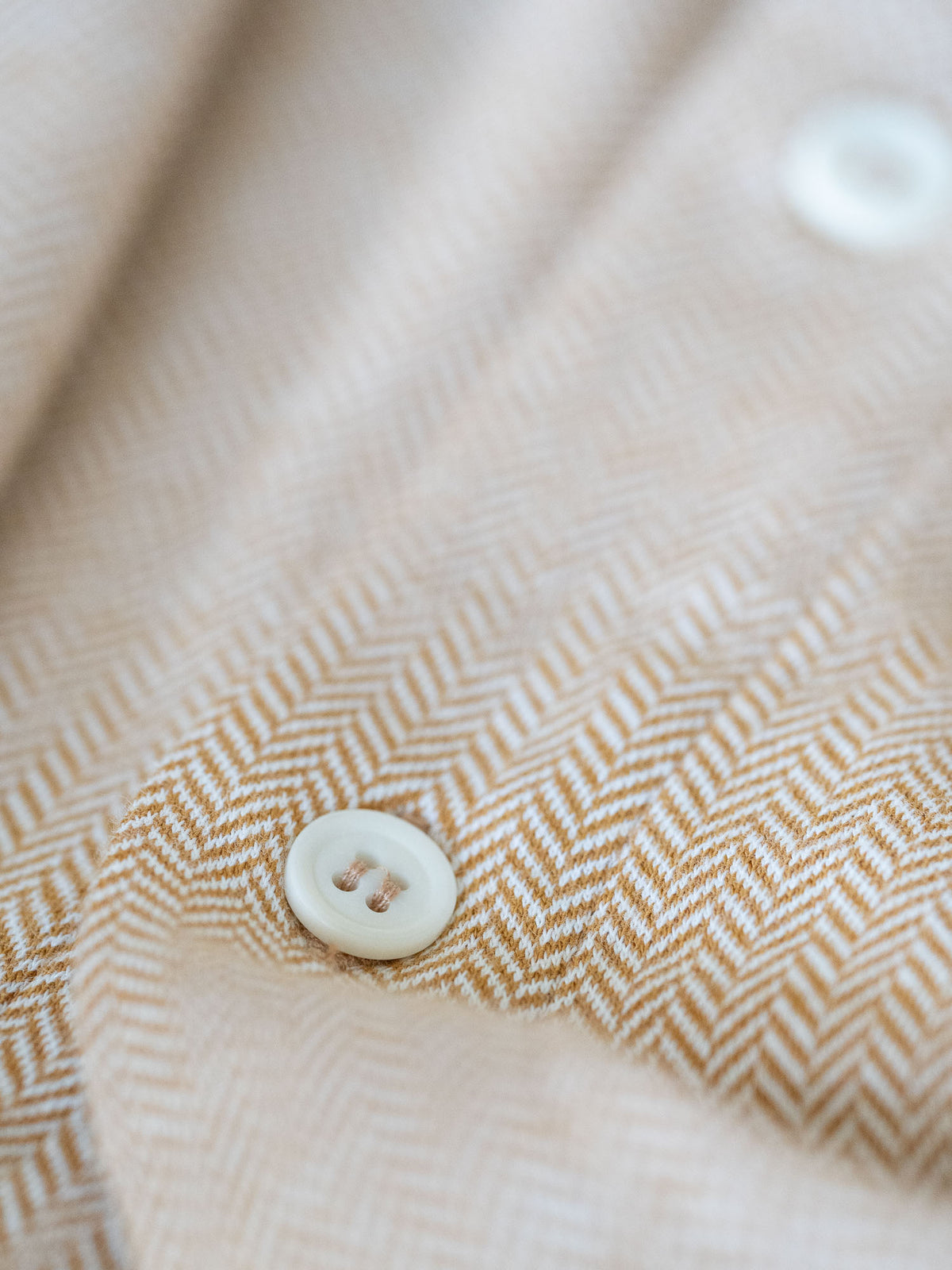 Detailaufnahme eines Männer Hemd von FUXBAU in senfgelb und einem Fishbone Muster aus 100% Biobaumwolle.