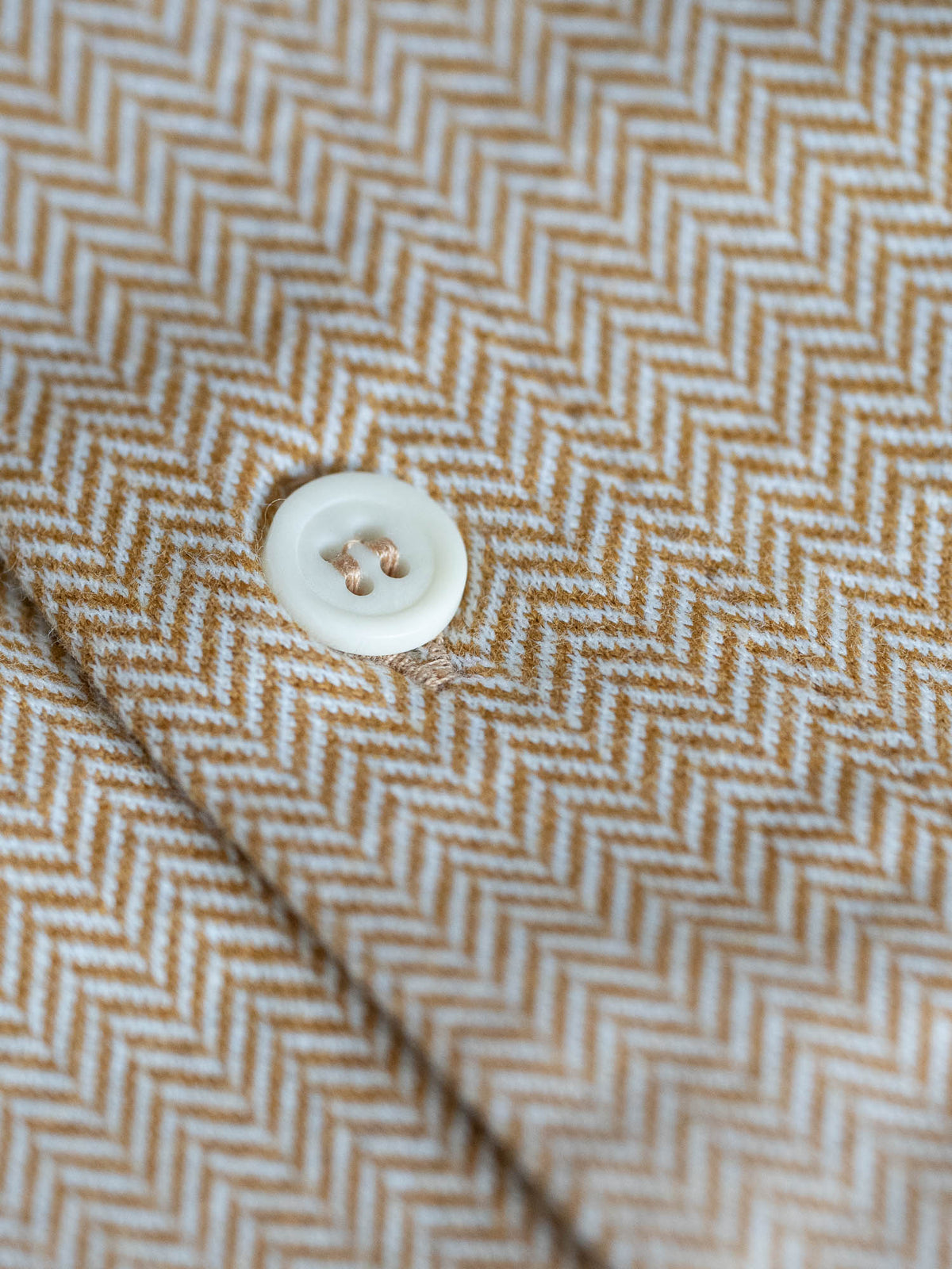 Detailaufnahme eines Männer Hemd von FUXBAU in senfgelb und einem Fishbone Muster aus 100% Biobaumwolle.