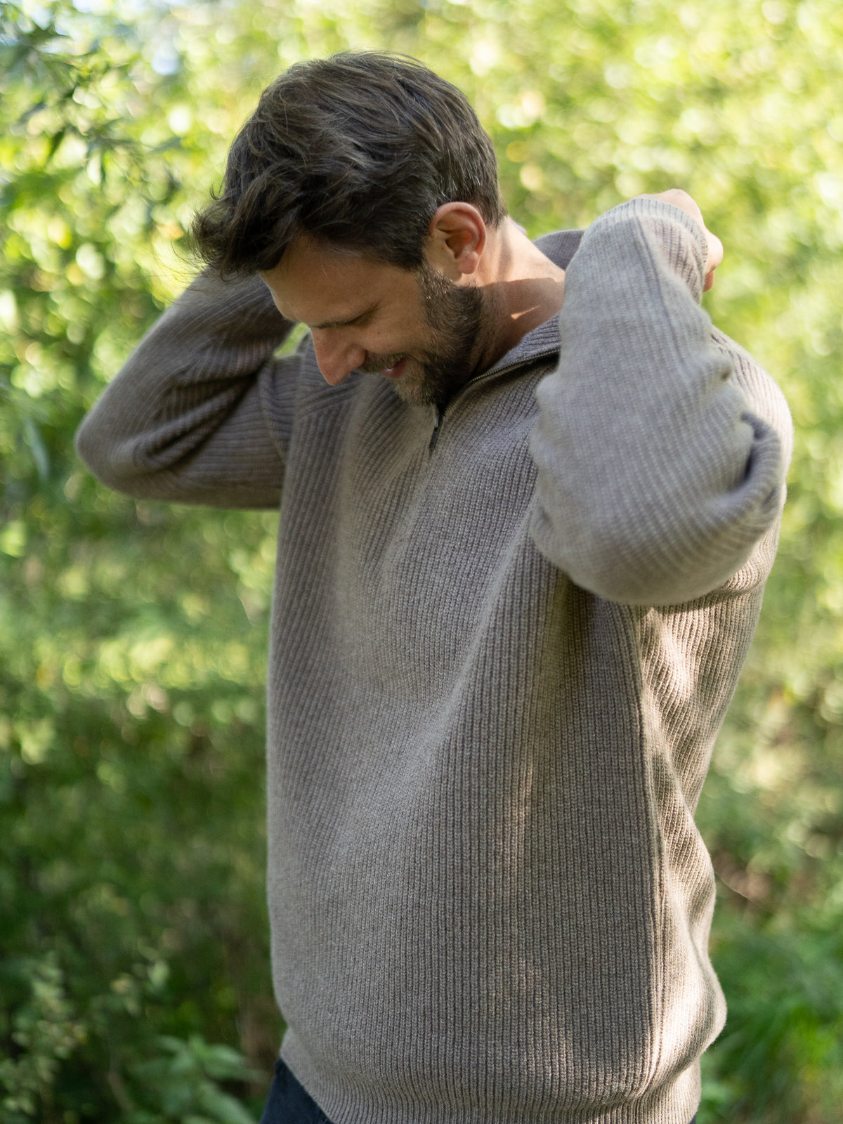Fair Fashion Männer Merino Troyer in braun meliert aus 100% Merino Schurwolle Made in Italy, getragen von einem jungen Mann der die Hand am Kragen hat.