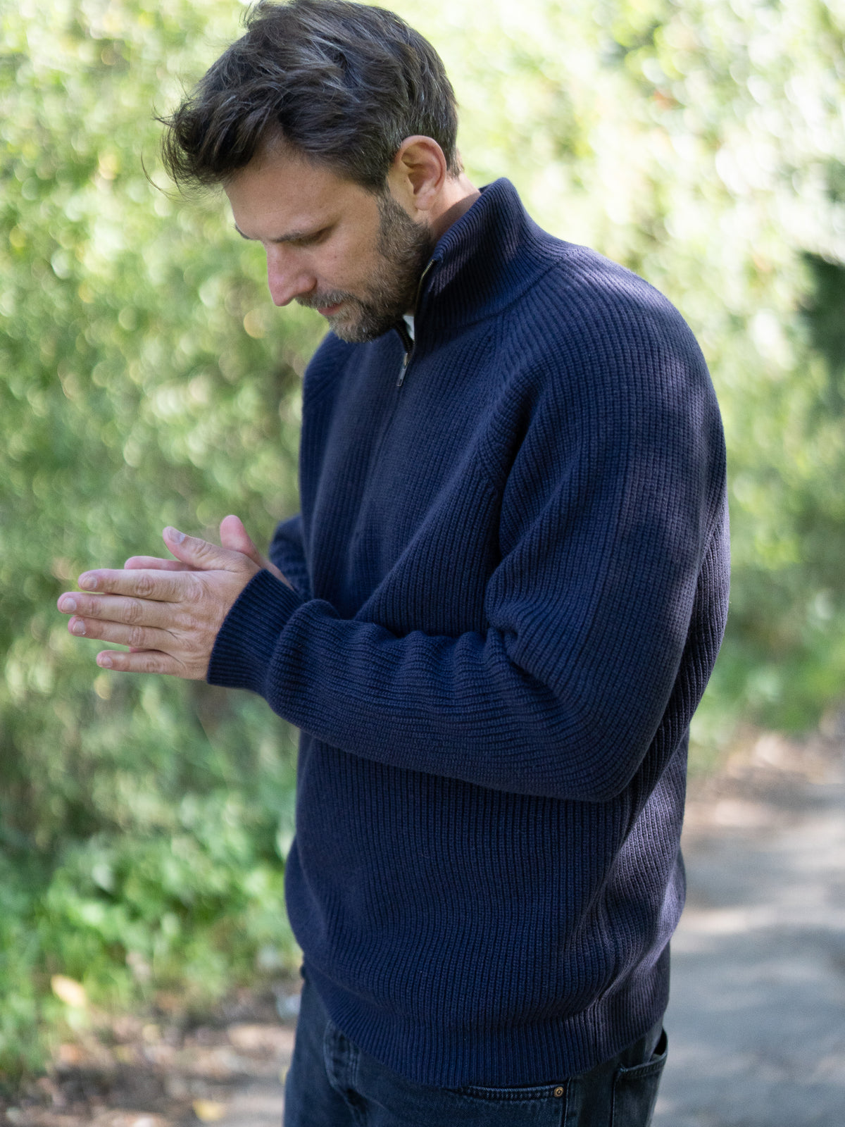 Fair Fashion Männer Merino Troyer in navy aus 100% Merino Schurwolle Made in Italy, getragen von einem jungen Mann der sich die Hände reibt.