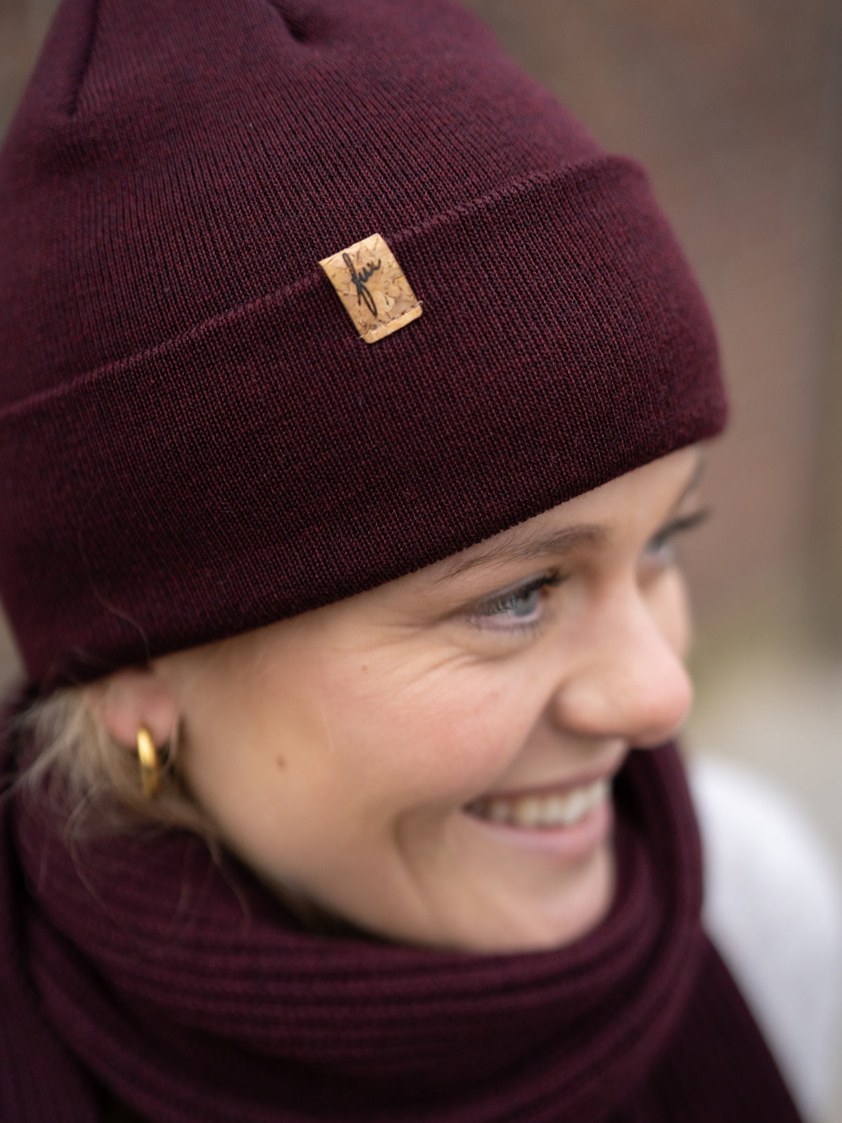 Greta trägt eine Fair Fashion FUXBAU Merino Kork Beanie aus Merino Schurwolle gestrickt in Deutschland in Bordeaux.
