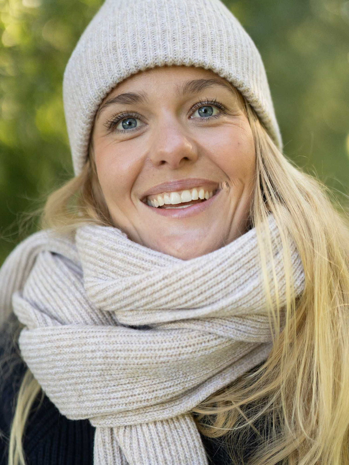 Merino-Schal extra lang in Beigemeliert mit beigemelierter Merino-Mütze – Fair-Fashion Outfit im Grünen.