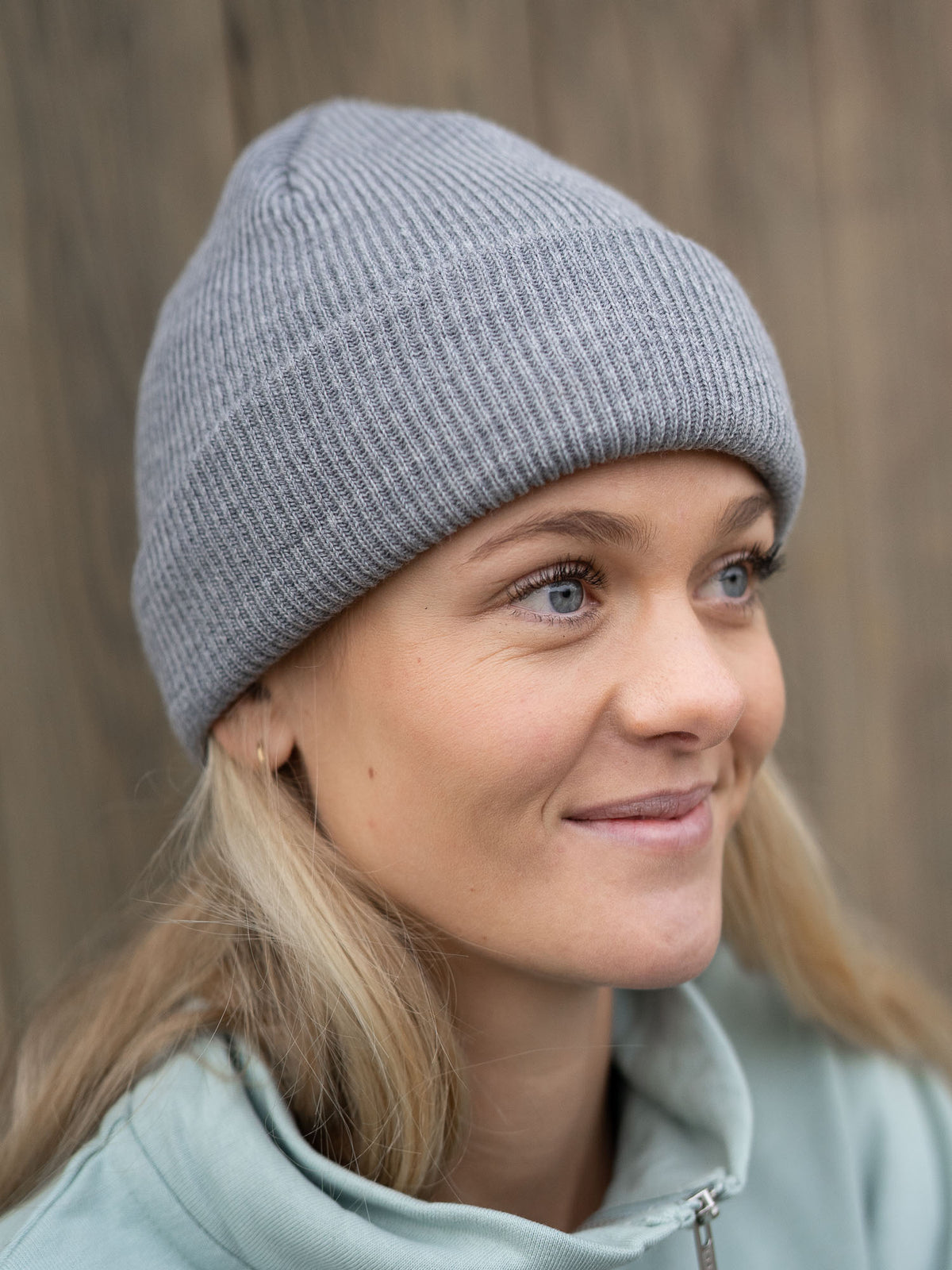 Junge, blonde Frau trägt eine fair gefertigte Merino Strickmütze von FUXBAU Made in Germany. GOTS zertifiziert.