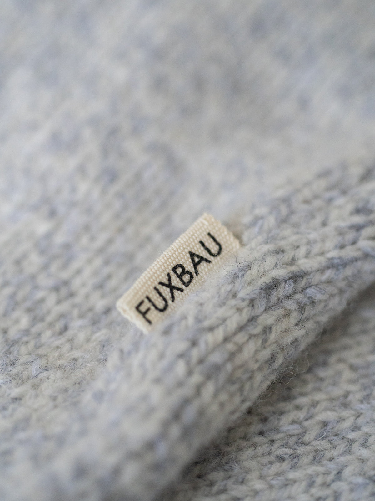 FUXBAU Label auf der graumelierten Strickweste aus Merinowolle – faire Produktion Made in Germany