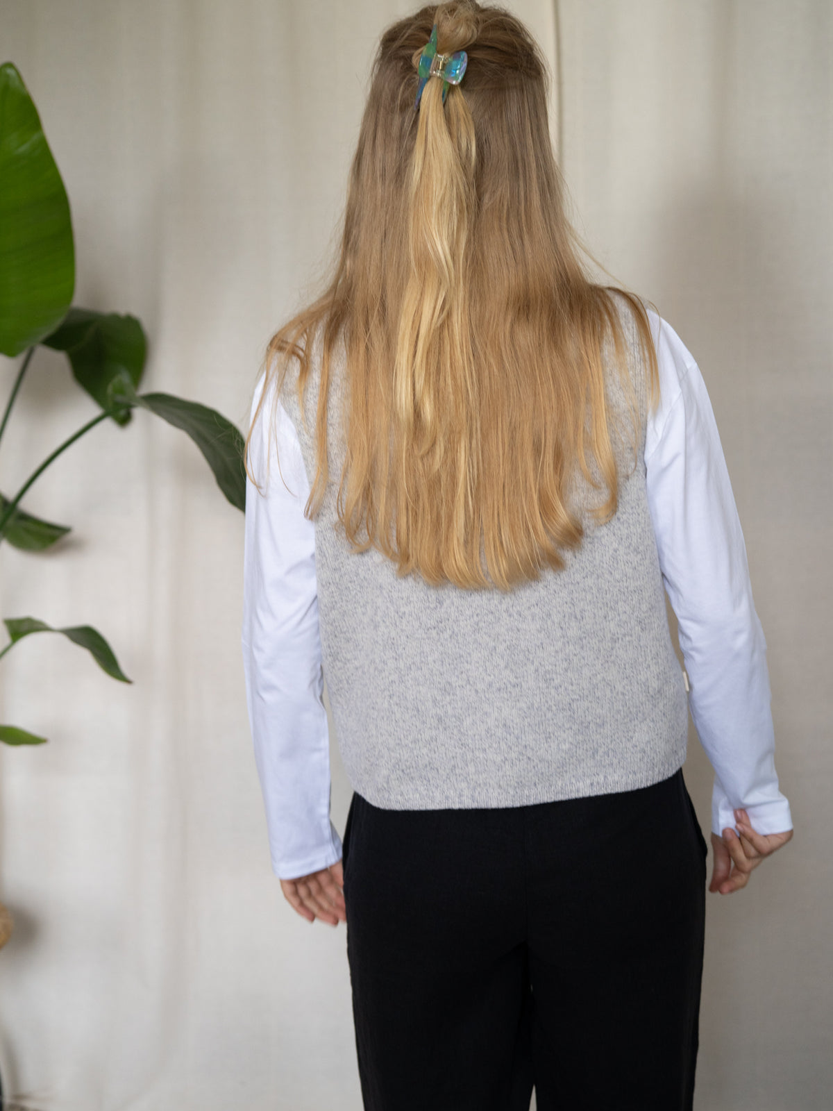 Rückansicht der FUXBAU Merino Strickweste Damen in Graumeliert – minimalistische, zeitlose Passform aus 100 % Merinowolle