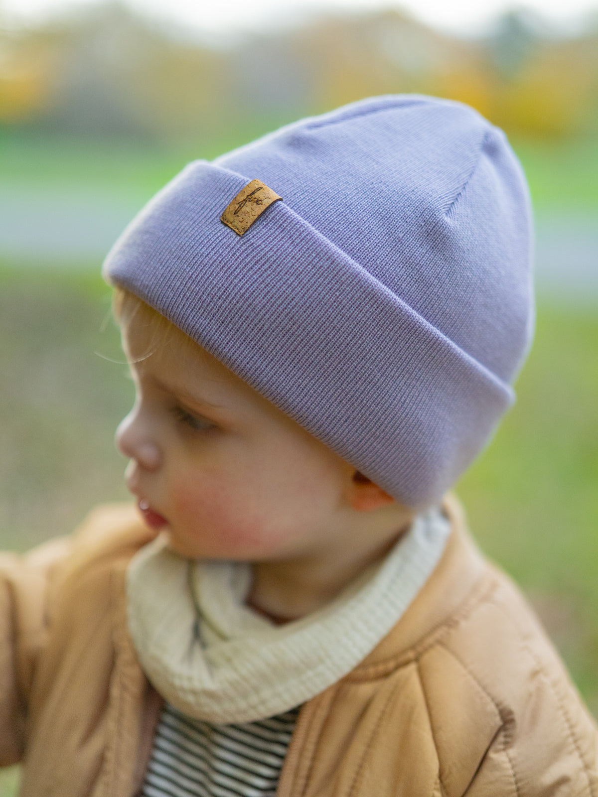 Kind trägt FUXBAU Kinder Beanie aus Merinowolle in Lavendel – Mütze mit Korklabel, fair gefertigt in Deutschland