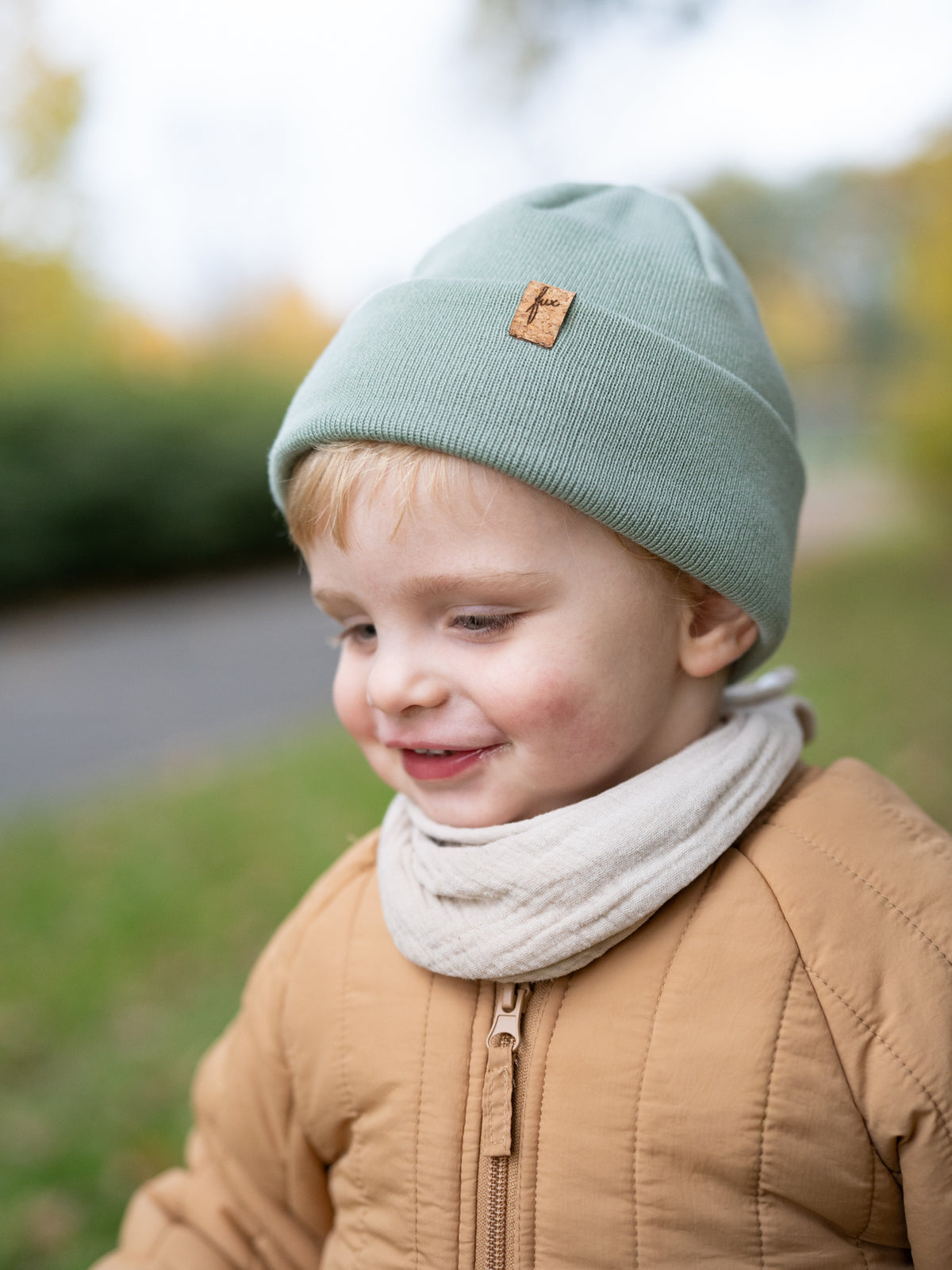 Kind mit FUXBAU Merino Beanie in Seegrün – Kinder Mütze mit Korklogo, fair produziert in Deutschland