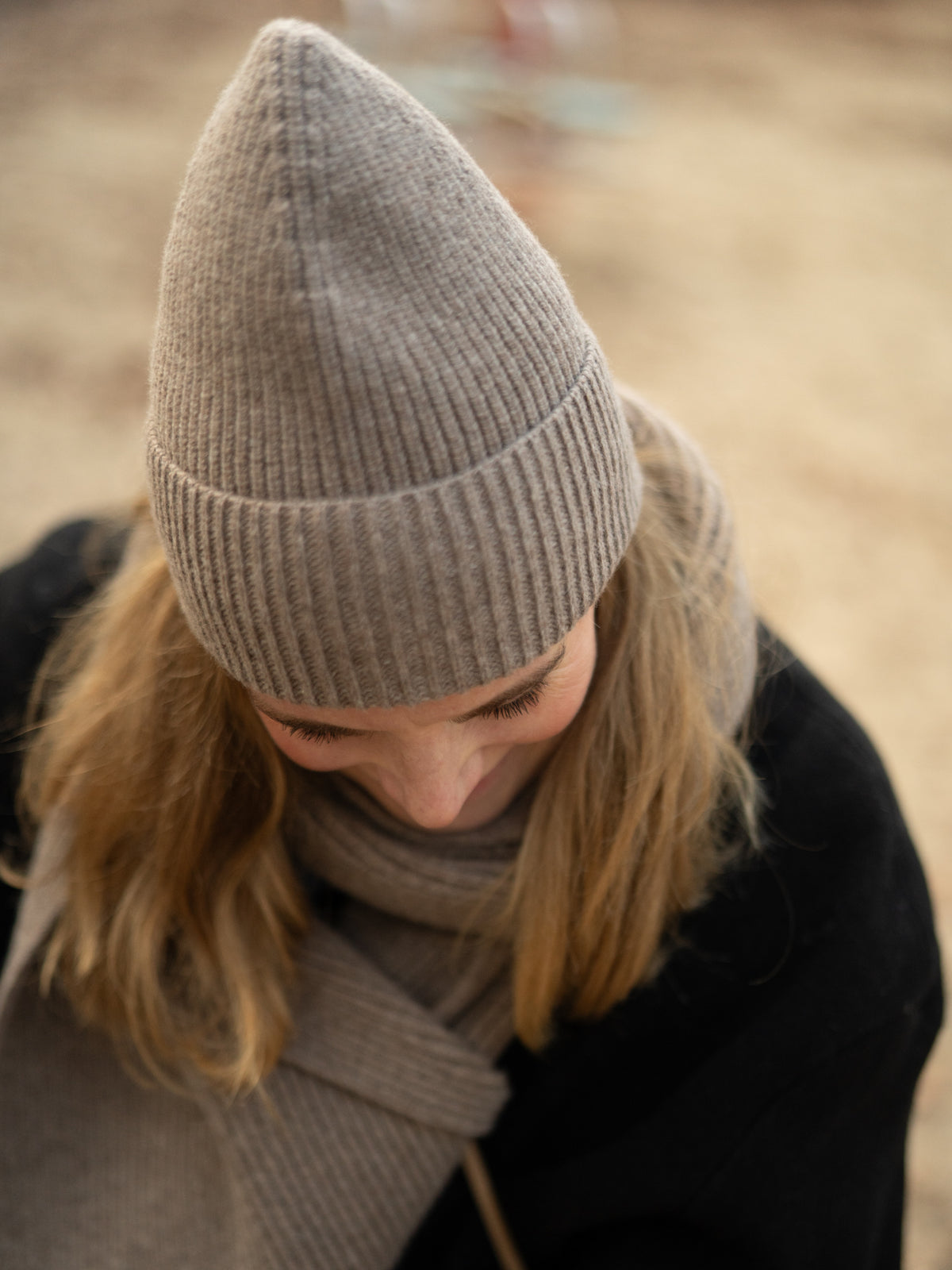 Frau trägt eine braunmelierte Merino Mütze von FUXBAU – weiche italienische Strickqualität, warm gefertigt.