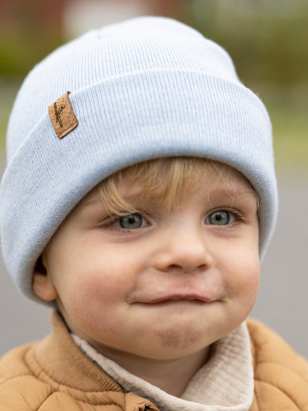 Kind mit eisblauer FUXBAU Kinder Merino Kork Beanie – Mütze aus 100% Merinowolle, fair produziert in Deutschland mit Kork-Patch.