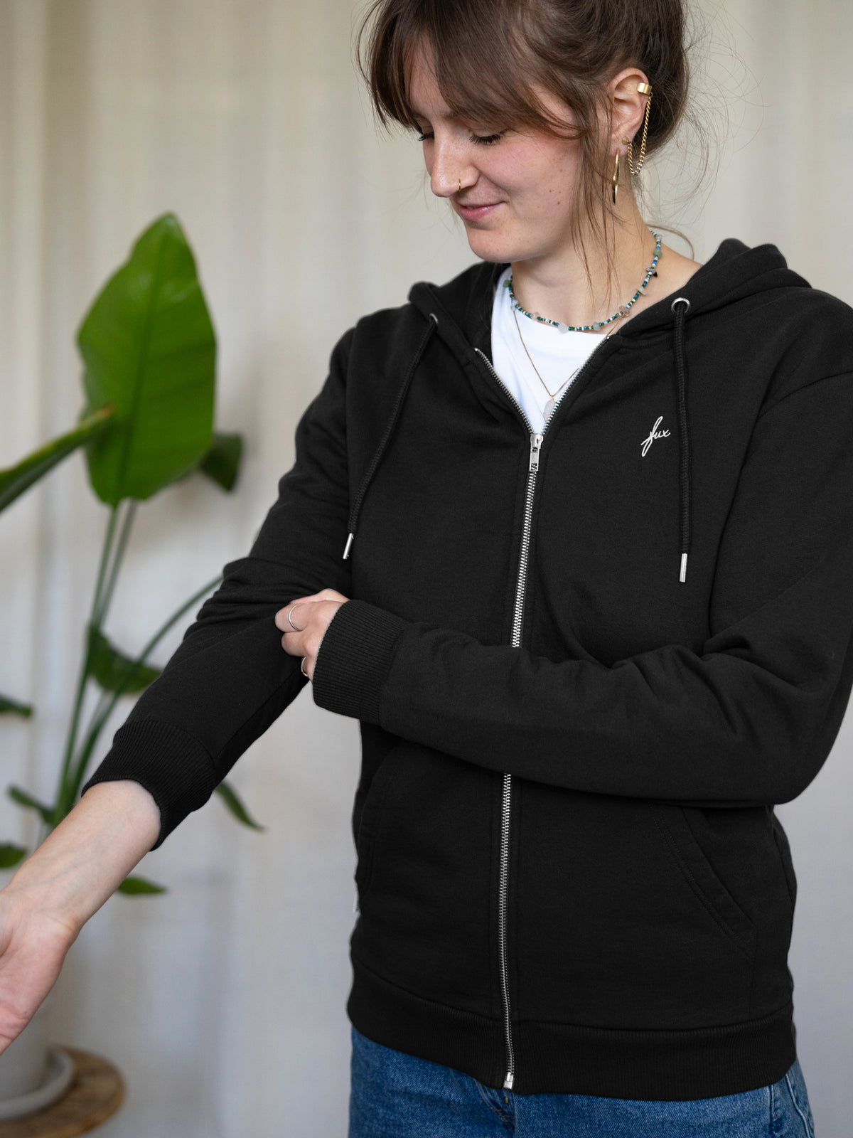 Unisex Sweatjacke in Schwarz aus Bio-Baumwolle – fair produziert in Portugal - getragen von einem dunkelhaarigen weiblichen Modell