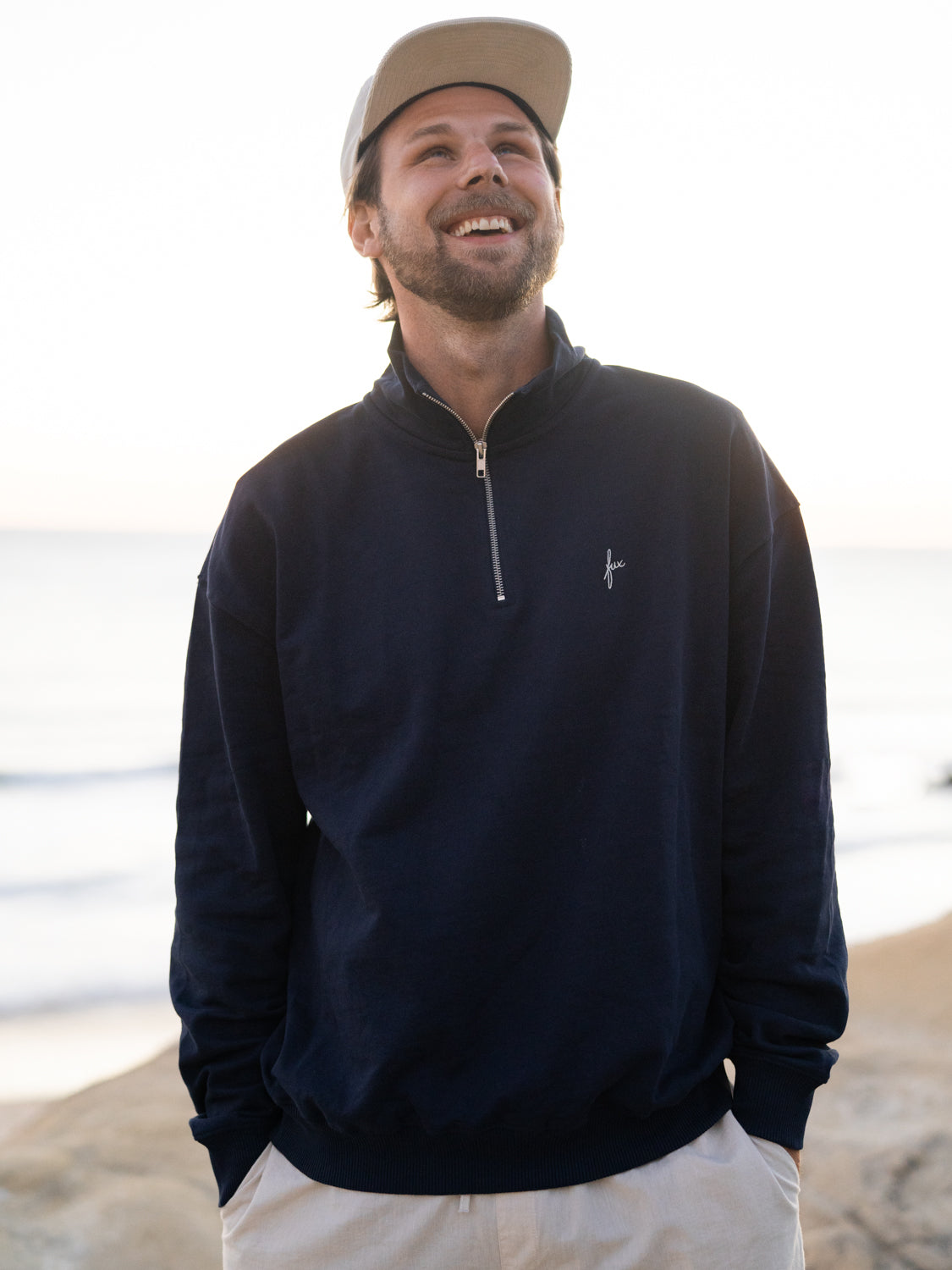 Half Zip Sweater in navy von FUXBAU aus Biobaumwolle getragen am Strand von Philipp in Spanien.
